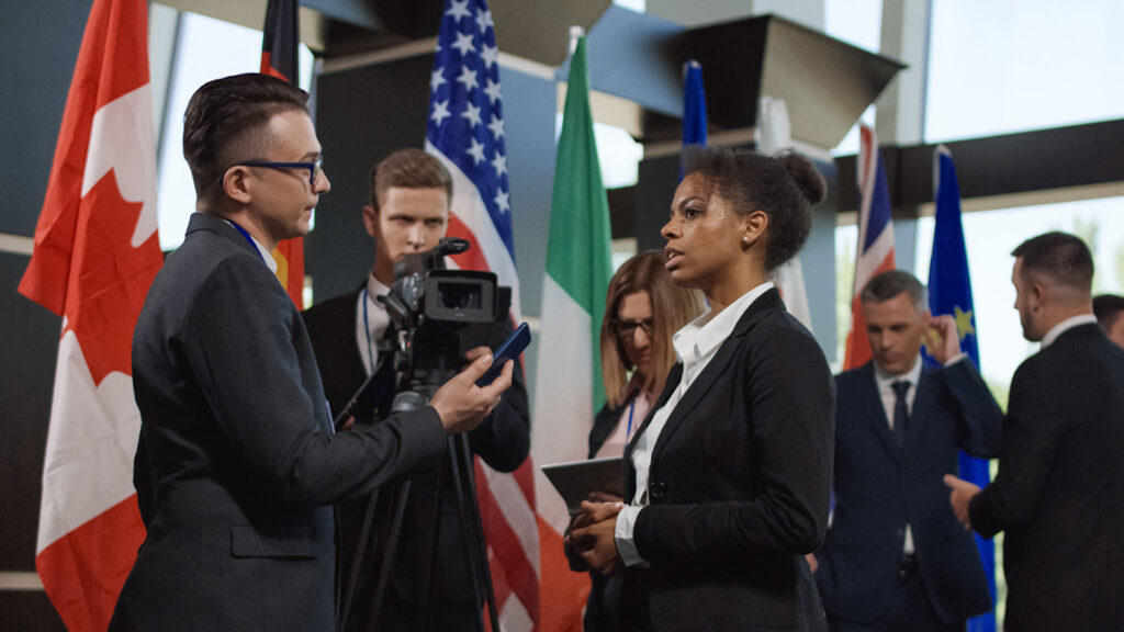 Formal African-American woman talking to journalist for camera and giving interview on international summit