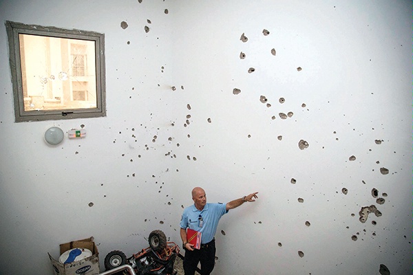 A man inside Bamako’s Radisson Blu Hotel points to large holes in a wall made by automatic weapons fire during the terrorist attack three days earlier. (United Nations Multidimensional Integrated Stabilization Mission in Mali)