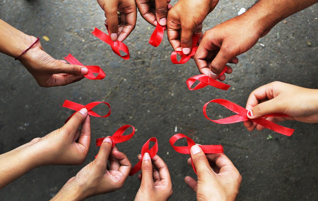 Handing Holding AIDS Ribbons [Photo credit: AP]