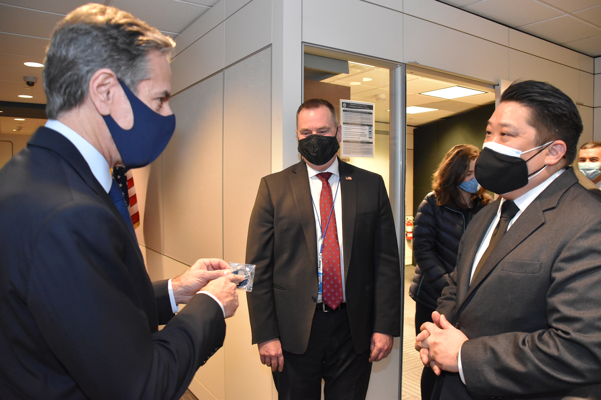 DSSCC Director Scott Kim (far right) gives a DSS coin to Secretary of State Antony J. Blinken (far left) as Acting Assistant Secretary of State for the Bureau of Diplomatic Security Todd J. Brown (center) looks on, Arlington, Va., February 21, 2021. (U.S. Department of State photo)