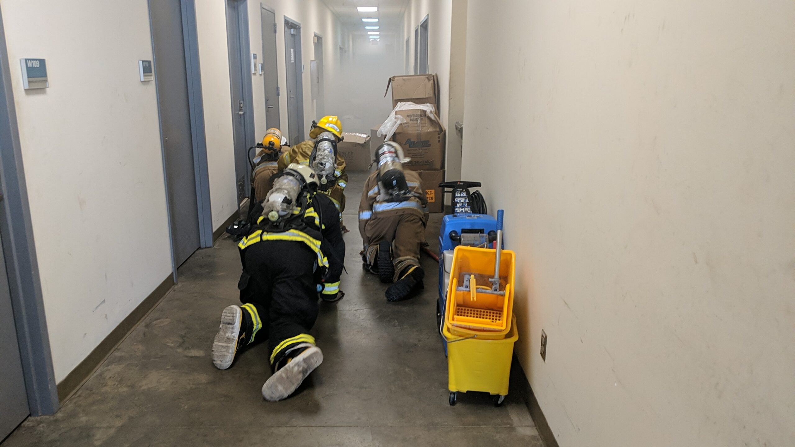 Members of the Liberia Fire Service crawl on the floor of a warehouse filled with artificial smoke to rescue two manikins placed there for them to locate and rescue, U.S. Embassy compound, Monrovia, Liberia, March 2021. (U.S. Department of State photo)