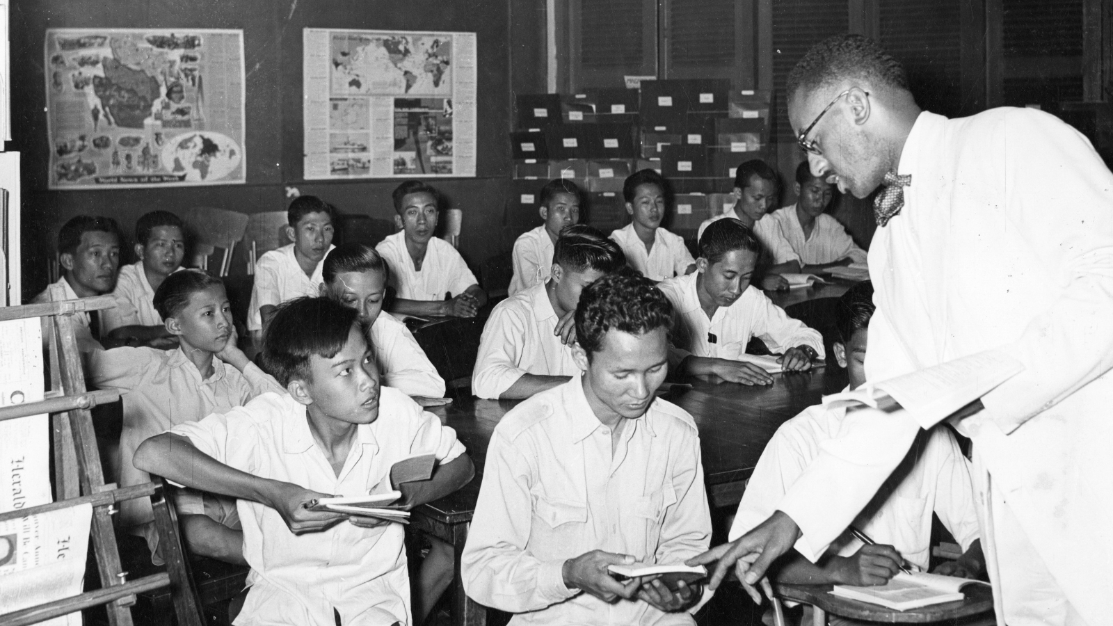 In the early years of the Fulbright Program in Cambodia, U.S. Fulbrighter Charles R. Sadler (right) teaches English to students in Phnom Penh from Ecole Descartes, Lycee Sisowath, Ecole Miche, and members of the city’s Police Department. (Photo courtesy of University of Arkansas Libraries Special Collections/ Public Domain)