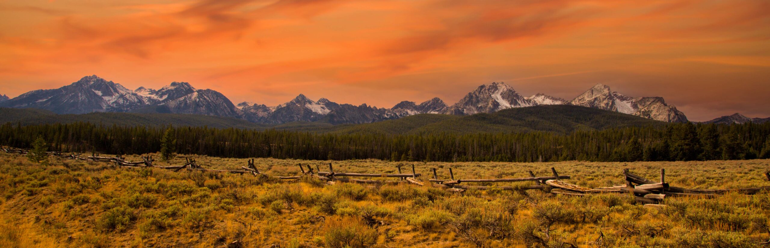 Panorama view of the Sawtooth mountains at sunset with a split rail fence