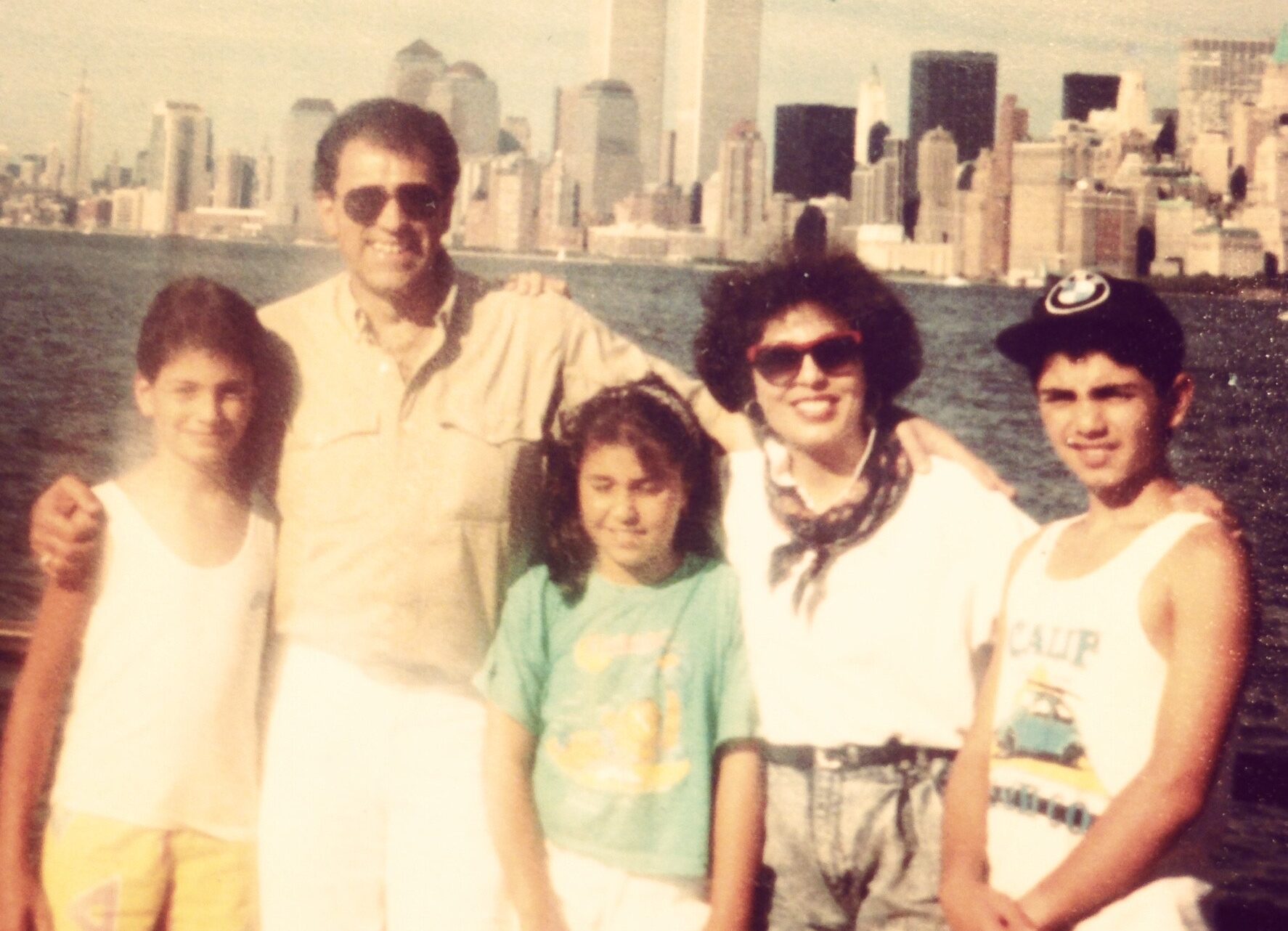 A mother, father, and their three children pose in front of the New York skyline in an old family photo