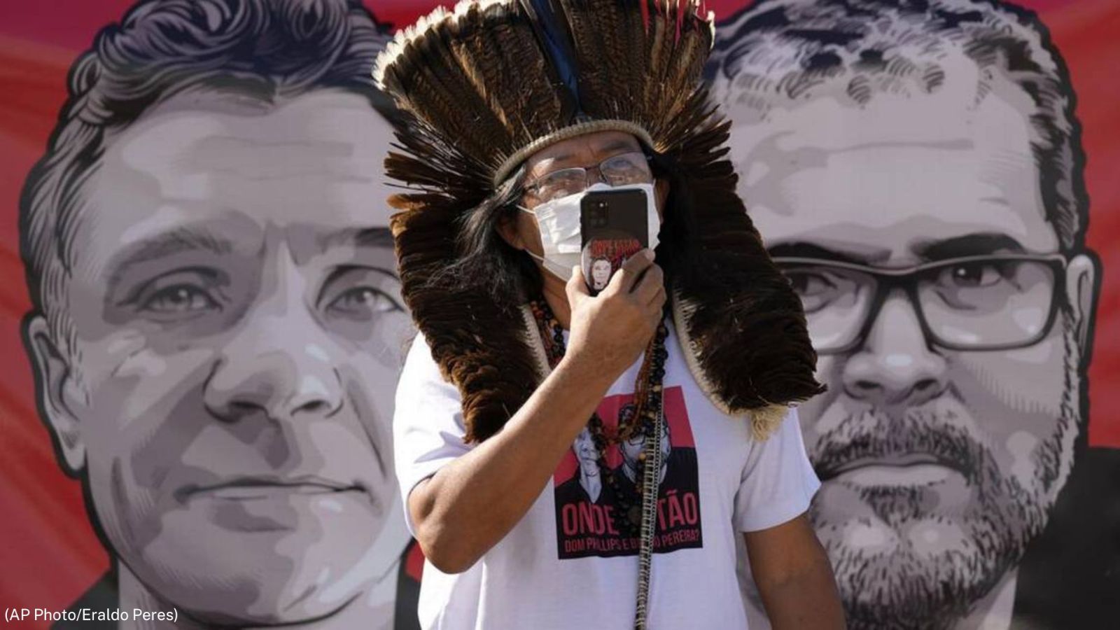 Indigenous leader Kamuu Wapichana stands in front of a banner with images of freelance British journalist Dom Phillips, left, and Brazilian Indigenous expert Bruno Pereira. [AP Photo by Eraldo Peres]