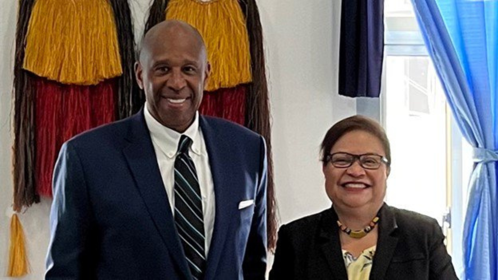 Bureau of Political-Military Affairs's Office of Global Programs and Initiatives’ Director, Mr. Michael Smith, and the Honorable J. Uduuch Sengebau Senior, Vice President and Minister of Justice, PW stand next to each other, smiling, in a bright room.