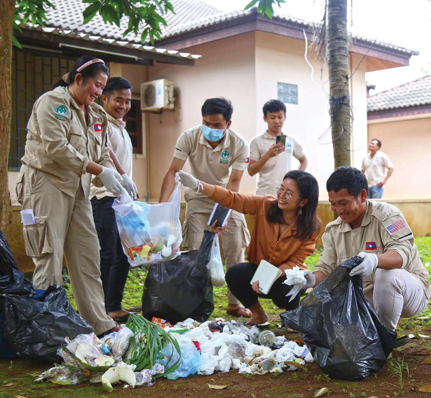 A group of people sort through office trash to pull out recyclable material.