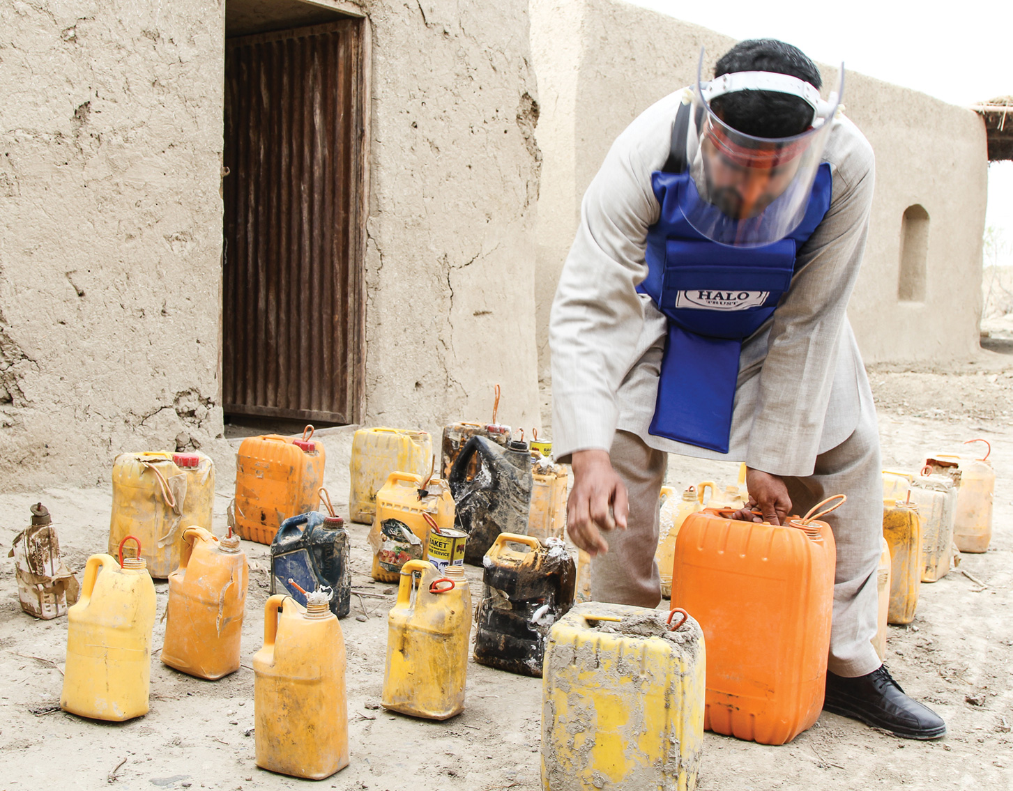 A person in protective gear leans over numerous plastic bottles