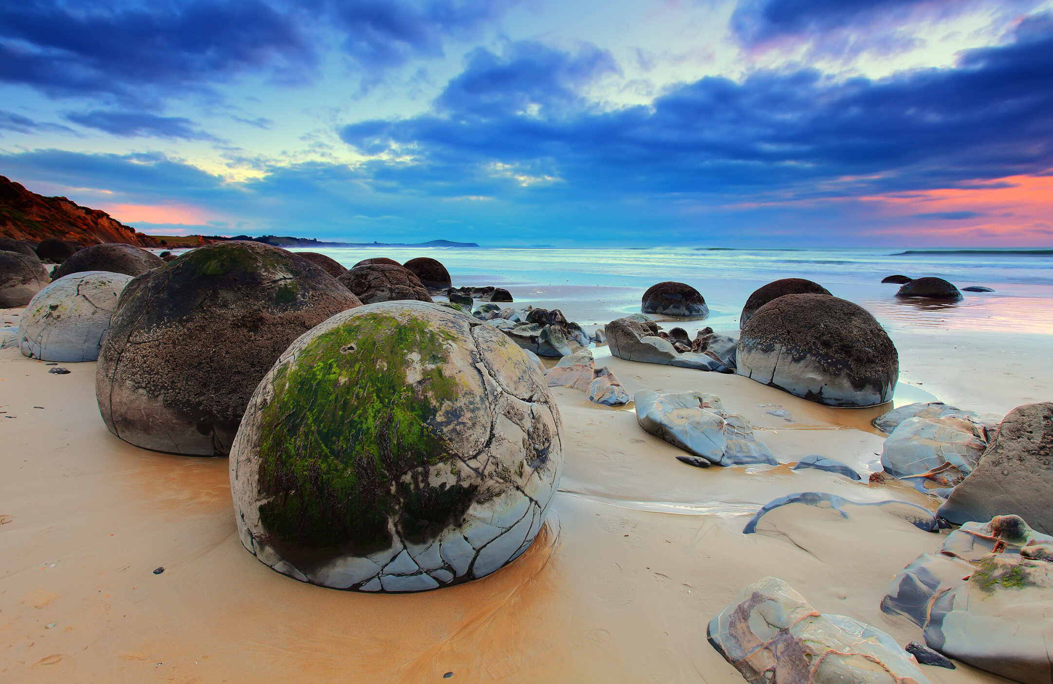 large rocks on sandy beach at sunrise