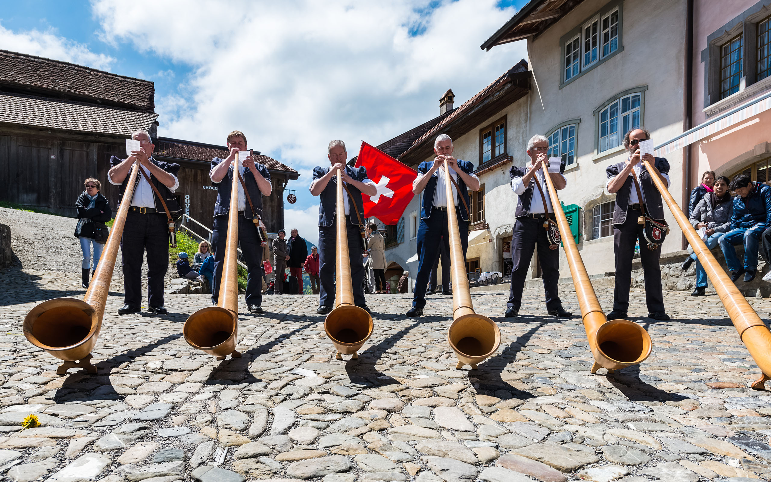 Cheese festival, Gruyere, Switzerland - May 4, 2014. Swiss musicians play the alphorn, typical instrument on the main street of the Gruyere village on May 4, 2014