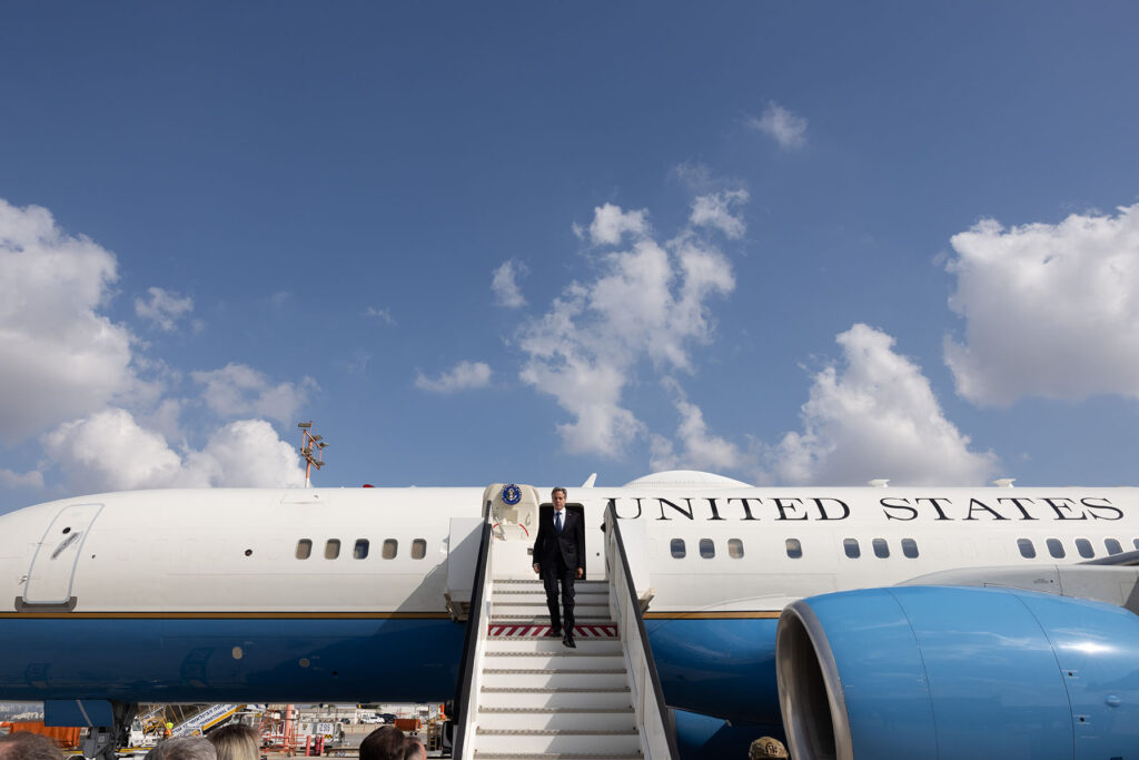 Secretary Blinken walks down steps from a plane